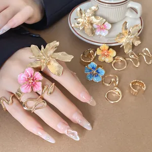 Primo piano di anelli con fiori 3D e fasce dorate ondulate sulla mano di una modella