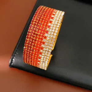 Primo piano di un bracciale rigido multistrato con strass sfumati rossi e trasparenti.
