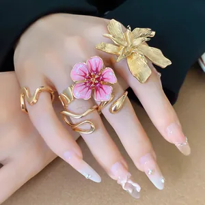 Vista ravvicinata di anelli a forma di fiore 3D rosa e oro indossati su una mano.