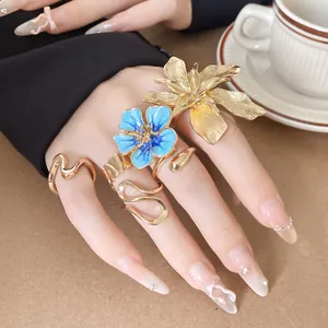 Vista dettagliata di anelli a fiore 3D blu e oro alla moda sulle dita della modella