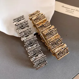 Detail view of retro metal bracelets with irregular geometric texture in gold and silver.