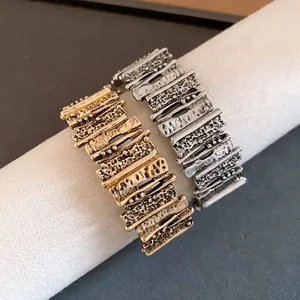 Close-up of vintage geometric metal cuff bracelets with textured gold and silver finish
