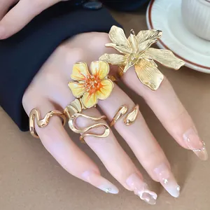 Vista dettagliata di eleganti anelli a fiore 3D dorati con finitura smaltata sulla mano