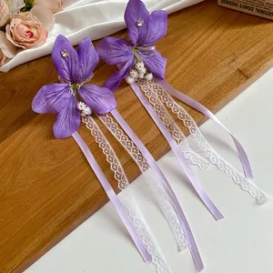 Détail de pinces à cheveux fleurs en tissu violet avec dentelle élégante et rubans en satin