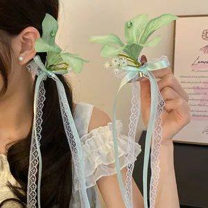 Vue détaillée d'une pince à cheveux fleur en tissu vert menthe avec dentelle et strass