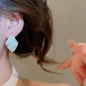 Primo piano di orecchini a perno a rombo argentati con zircone scintillante su modella