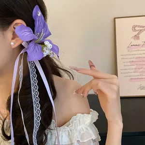 Vue détaillée d'une pince à cheveux fleur violette avec rubans dentelle et strass