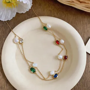 Close-up detail of layered gold necklace with oval colorful zircons and freshwater pearls