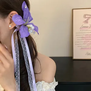 Vue détaillée de la pince à cheveux fleur en tissu violet avec dentelle et rubans de soie