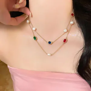 Close-up detail of a layered gold-tone necklace featuring oval colorful stones and pearls