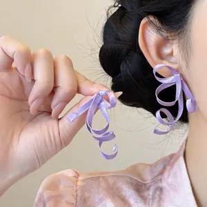 Close-up of purple anti-gravity ribbon bow earrings with unique swirling design
