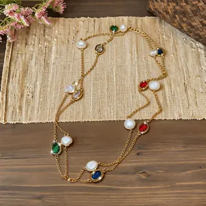 Elegant gold chain necklace featuring oval colored zircons and white pearls macro detail