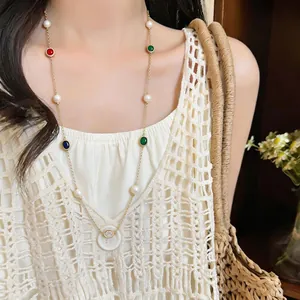 Close-up of long necklace with colorful zircons, pearls, and a white button pendant.
