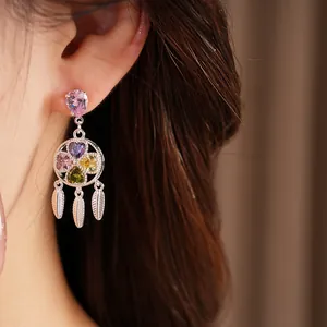 Close-up detail of silver-toned tassel earrings with multi-colored heart-shaped zircon stones