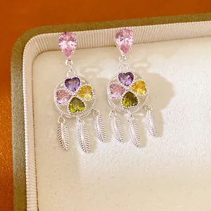 Close-up of vintage silver earrings with multi-colored heart-shaped zircons and feathers