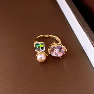 Detailed view of an elegant gold open ring with purple stone, crystal, and pearl decoration