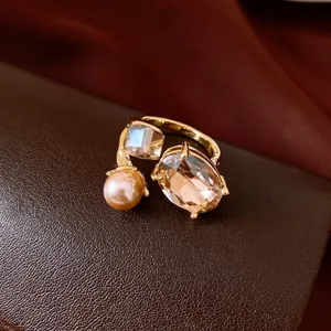 Close-up of elegant gold open ring featuring an oval gemstone and a pink pearl