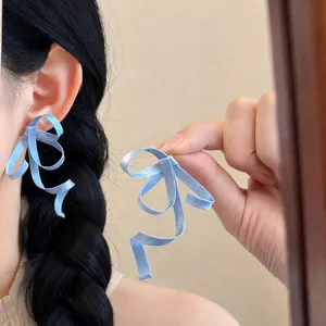 Macro view of blue ribbon bow earrings featuring a unique anti-gravity flowing design.