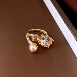Detailed macro view of a golden open ring with elegant oval champagne crystal and pearl
