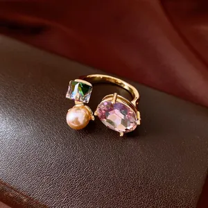 Macro detail of elegant open ring featuring oval pink crystal, square gem and pearl