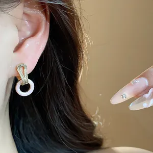 Nahaufnahme von 14k vergoldeten Zirkonia-Ohrringen mit rundem rosa Emaille-Anhänger