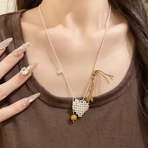 Close-up of woven heart pendant necklace with tassel and bead details on model