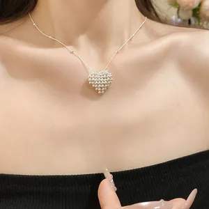 Close-up of a delicate silver woven heart pendant necklace on a minimalist clavicle chain