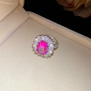 Detailansicht eines funkelnden rosa Zirkonia-Blumenrings in einer beigen Schmuckschatulle