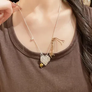 Minimalist woven heart pendant necklace with tiger's eye bead and brown tassel detail