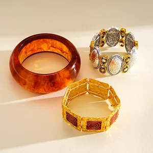 Vista dettagliata di tre bracciali geometrici in metallo vintage e un bracciale in resina