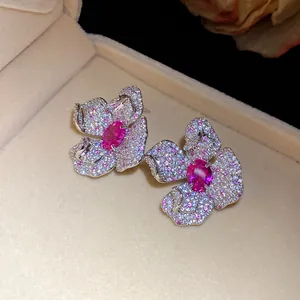 Nahaufnahme eleganter Blumenohrringe mit rosa und weißen Pavé-Zirkoniasteinen.
