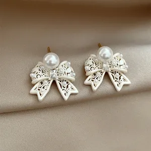 Close-up of French vintage hollow bow earrings with elegant white pearls and crystals