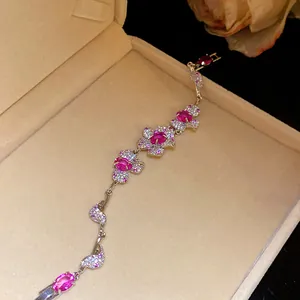 Detailaufnahme eines eleganten silbernen Armbands mit rosa Zirkonia-Blumenanhängern