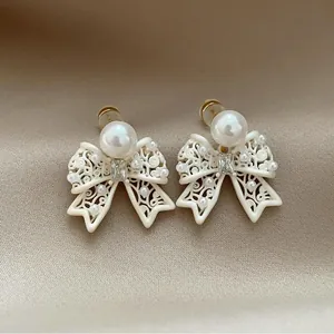 Detailed close-up of French vintage hollow-out bow earrings with a large white pearl