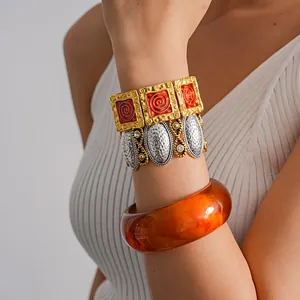 Primo piano di bracciali vintage in metallo e rigido in resina ambrata sul polso