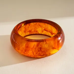 Vista ravvicinata di un bracciale rigido in resina ambrata con venature interne