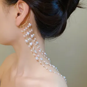 Detailed view of elegant multi-layered pearl tassel ear cuff wrap on model's ear