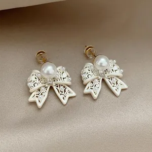 Detail shot of French vintage white bow earrings with hollow pattern and pearls