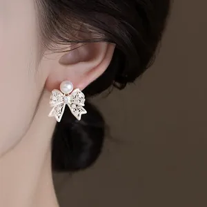 Macro detail of elegant vintage bow earring with a white pearl on a model's ear
