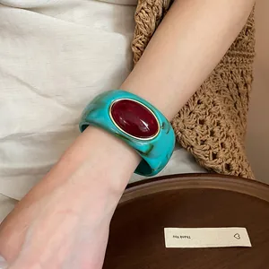 Vista dettagliata di un bracciale rigido vintage in acrilico turchese con pietra rossa