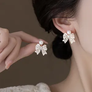 Elegant French vintage hollow bow earrings featuring a pearl and crystal inlay detail.