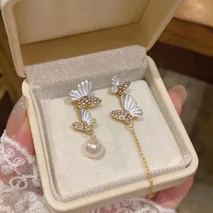 Elegant asymmetric butterfly earrings with shell wings and pearl drops in gold finish