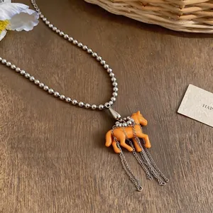 Playful orange resin horse pendant necklace with silver ball chain and long chain tassels.