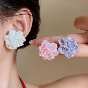 Primo piano di eleganti orecchini a perno a forma di rosa in resina perlata sul modello