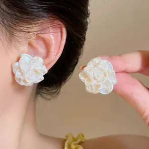 Primo piano di eleganti orecchini a fiore in resina bianca con finitura perlata lucida.