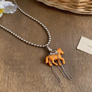 Macro view of a cute orange resin horse pendant necklace with silver tassel chains