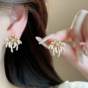 Close-up of elegant 18k gold-plated firework stud earrings with zircons and enamel.