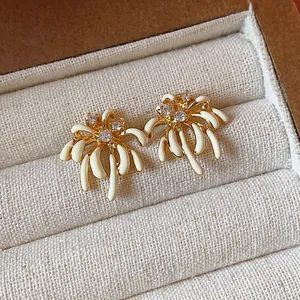 Close-up view of elegant 18k gold plated fireworks stud earrings featuring white enamel and zircons