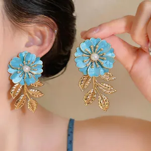Detailansicht blauer Emaille-Blumenohrringe mit Perle und goldenen Blattquasten
