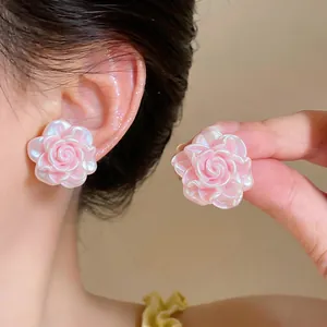 Dettaglio di orecchini a lobo a forma di rosa in resina rosa indossati all'orecchio